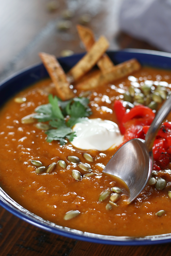 Sweet Potato Soup in a blow bowl with roasted pumpkin seeds and sour cream.