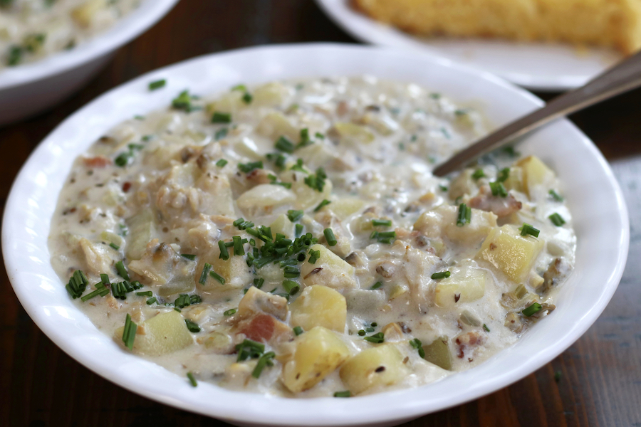 Thick New England Clam Chowder Recipe in white bowl sitting on a wooden table.