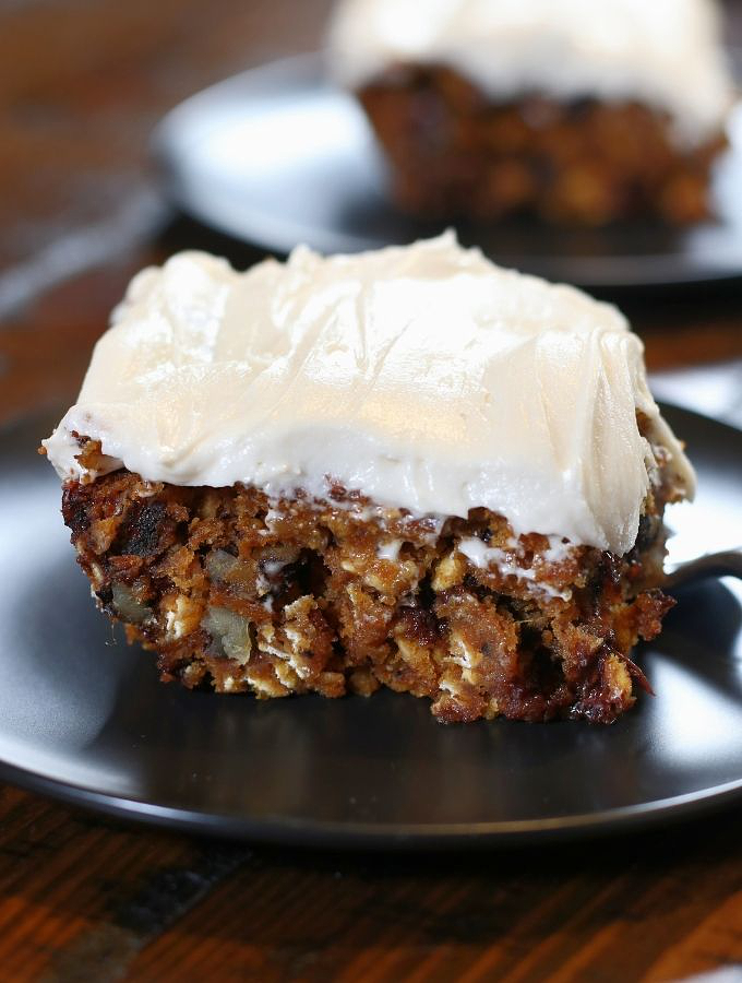 A slice of frosted Healthy Pumpkin Cake sitting on a black plate.