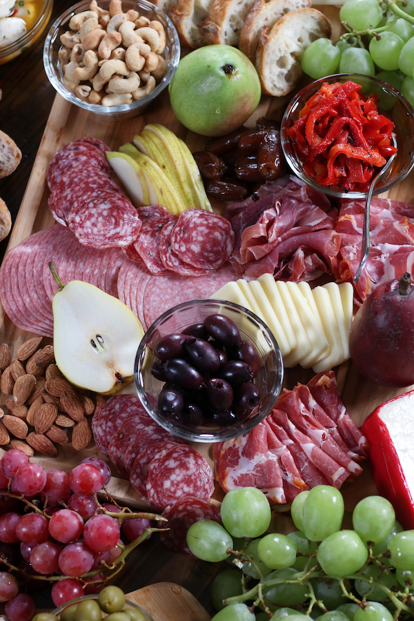 A wooden cutting board holding Italian Charcuterie Board ingredients.