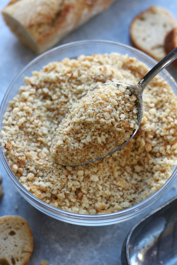 Spoonful of DIY Breadcrumbs being taken out of a bowl.