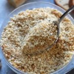 A spoon full of Homemade Breadcrumbs over a bowl of breadcrumbs.