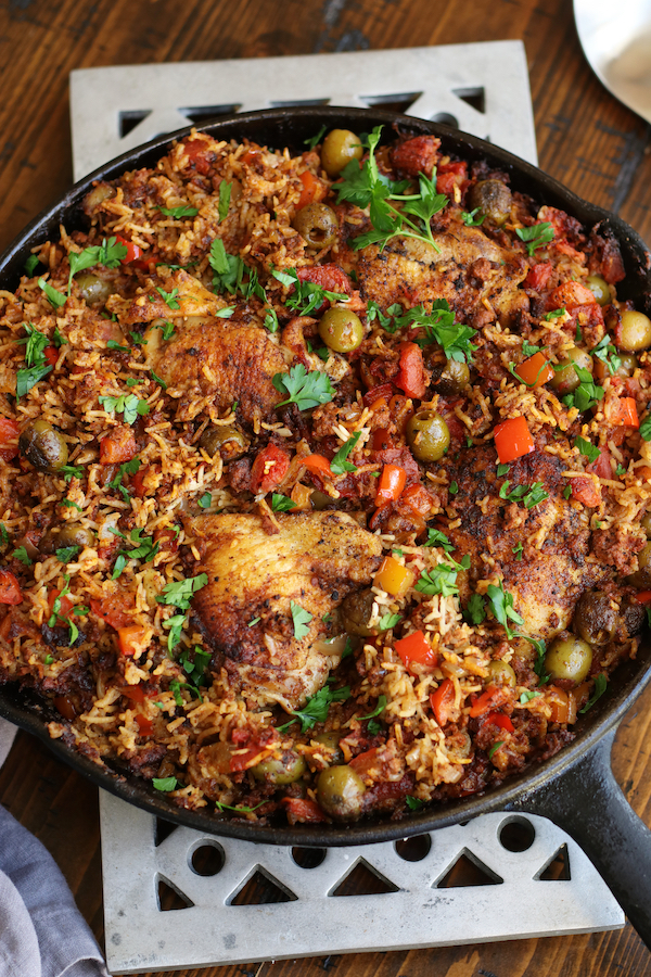 Chicken and Chorizo with rice, green olives, red bell pepper and garnished with parsley.