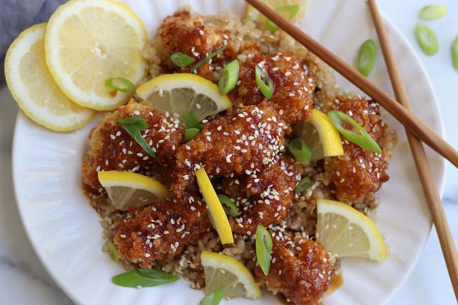 Chinese Lemon Chicken that has been baked and garnished with sesame seeds, lemon slices and green onions.