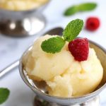 A serving of Lemon Sorbet garnished with a raspberry and fresh mint leaves.
