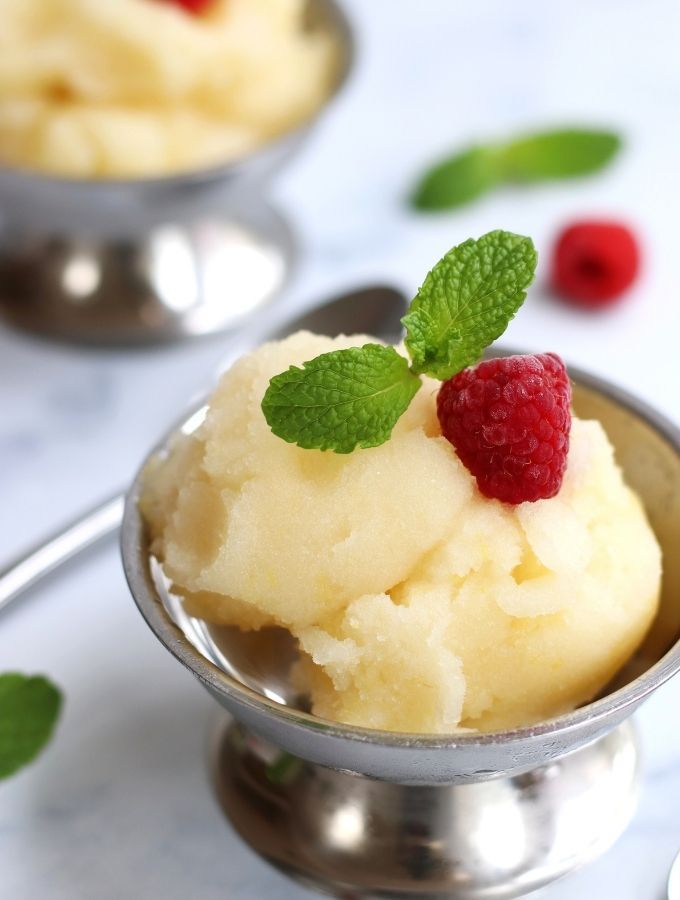 A serving of Lemon Sorbet garnished with a raspberry and fresh mint leaves.