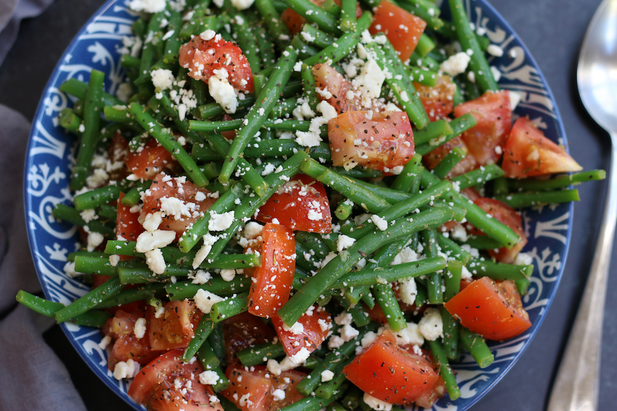 Marinated Green Bean Salad garnished with feta and black pepper.