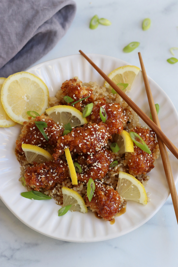 A serving of Sticky Lemon Chicken sitting on a bed of short grain brown rice.