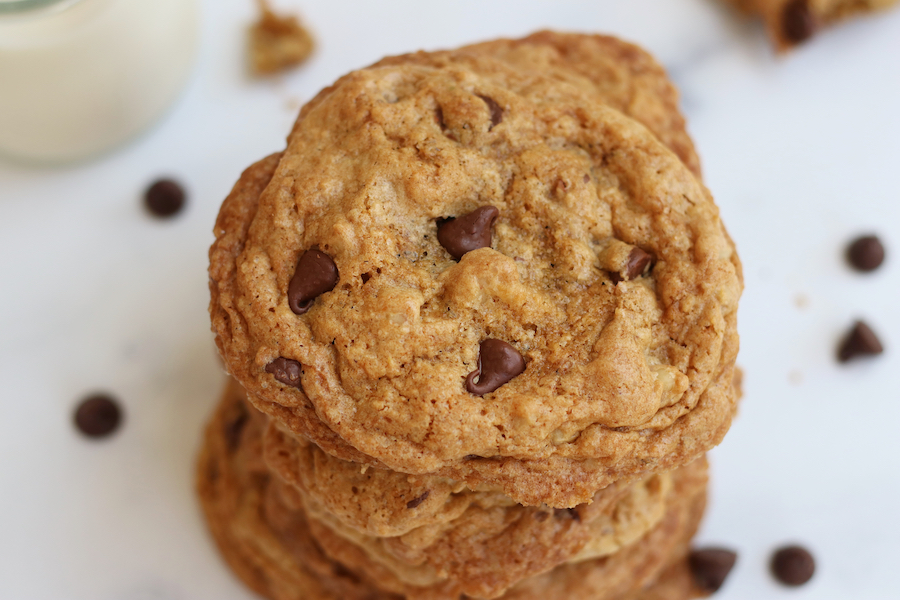 A stack of the Best Vegan Chocolate Chip Cookies sitting on a white counter with chocolate chips.