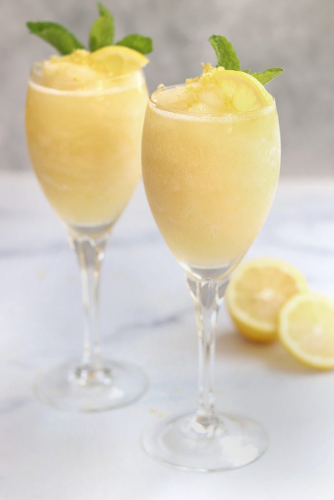 Two crystal glasses of a Lemon Dessert Cocktail sitting on a white countertop.