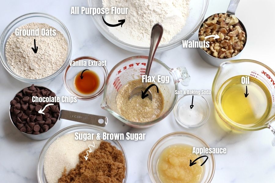 Ingredients for Vegan Chocolate Chip Cookies measured into small bowls laying on a white countertop.