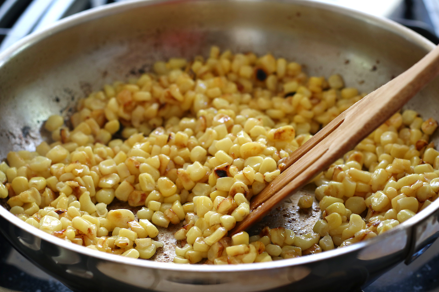 A stainless steel frying pan full of Pan Roasted Corn for Summer Pasta Salad.