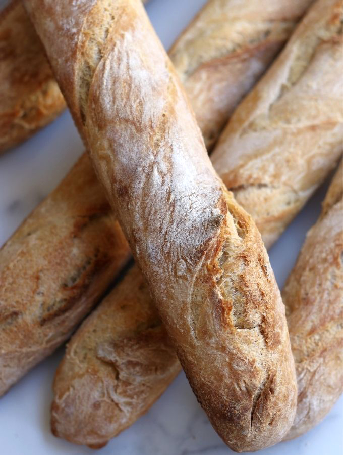 Sourdough Baguettes sitting on a white counter.