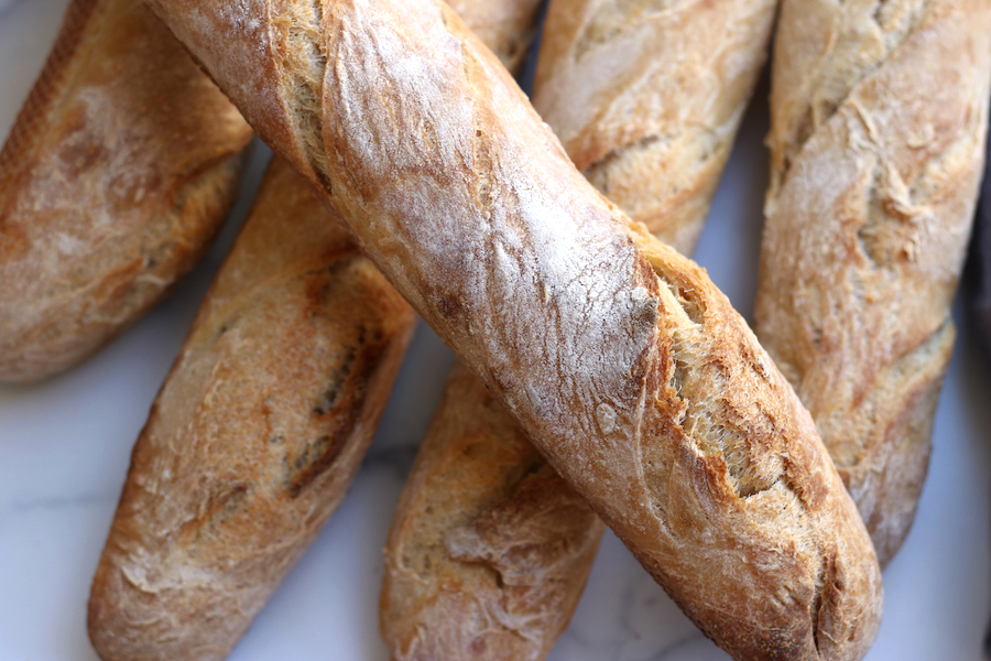 Sourdough French Baguette sitting on top of four other baguettes.