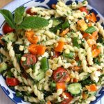 Overhead photo of Summer Pasta Salad with orange bell pepper pieces, fresh mint and chives.