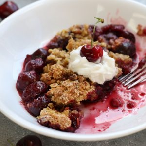 Half eaten Cherry Crumble served in a white bowl.