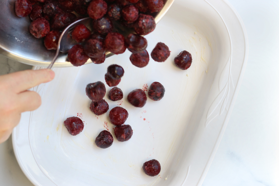 Adding cherries to a baking pan.