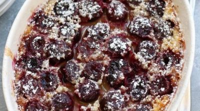 Over head photo of Cherry Clafoutis in a white baking pan with handles.