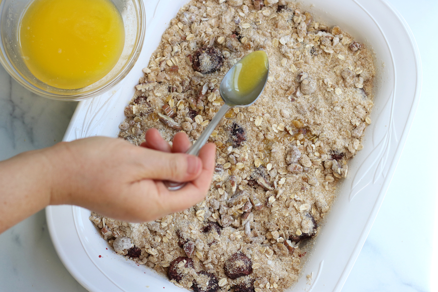 Drizzling butter on Cherry Crisp.