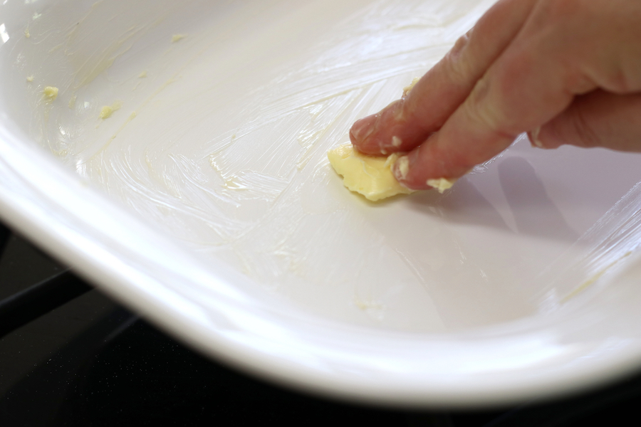 Greasing a baking pan with butter for Cherry Crisp.