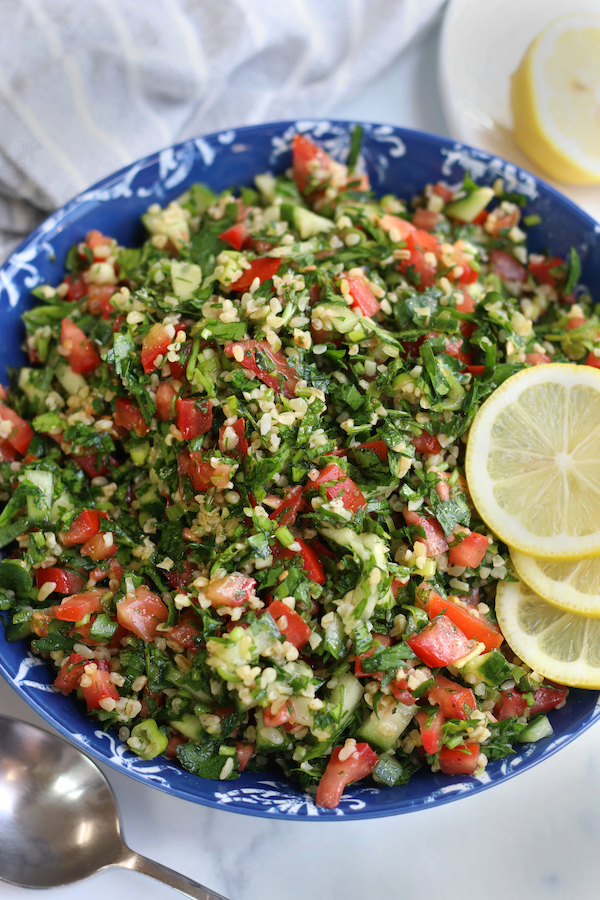 Overhead photo of Tabbouleh in a blue bowl sitting next to a serving spoon.