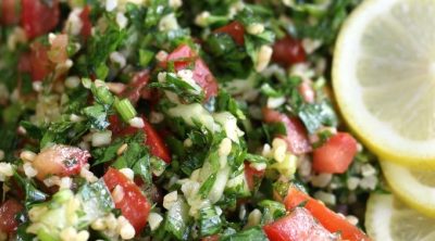 A bowl of Tabouli Salad garnished with fresh lemon slices.