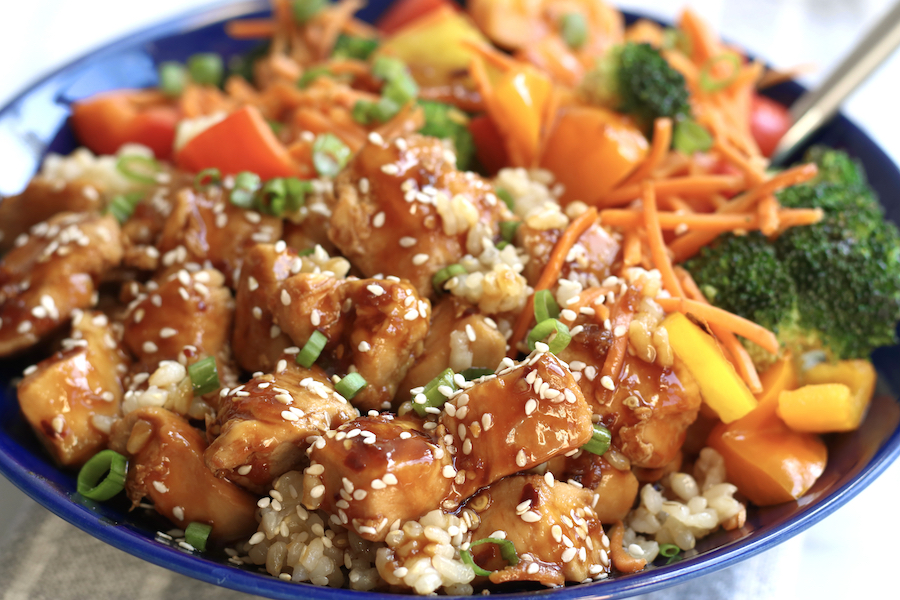 Up close photo of Terriaki Chicken Bowl with brown rice, broccoli, bell peppers and matchstick carrots.