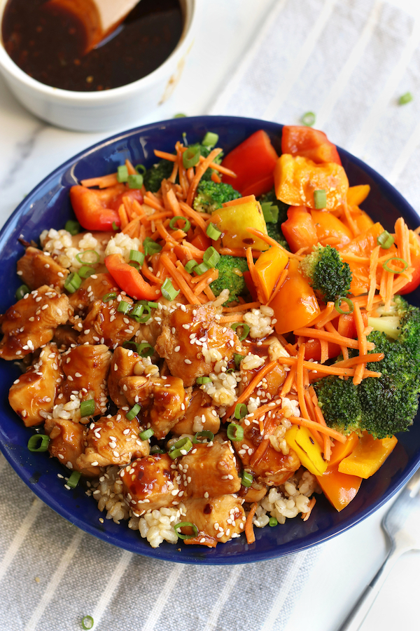 A serving of Teriyaki Chicken Rice Bowl garnished with green onions and sesame seeds.