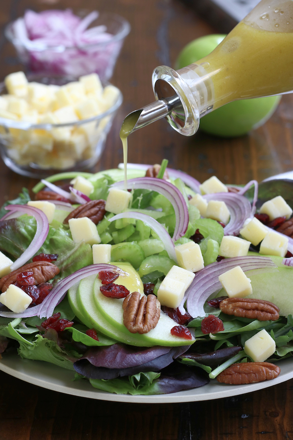 Zesty Apple Cider Vinaigrette being drizzle on a plate of salad.