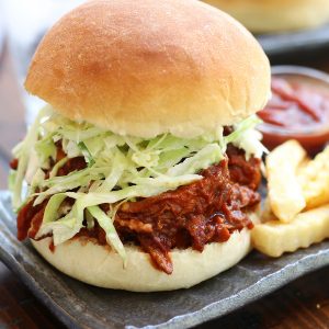 Pulled BBQ Chicken Sandwich on a grey plate with fries and ketchup.