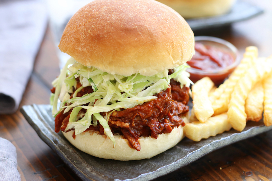 Pulled BBQ Chicken Sandwich on a grey plate with fries and ketchup.