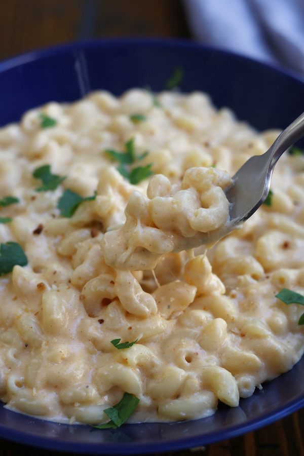 A fork dipping into a serving of Homemade Mac and Cheese served in a blue bowl.