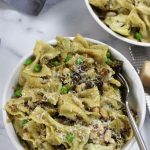 Pasta with White Beans in a white bowl with shaved parmesan on top.