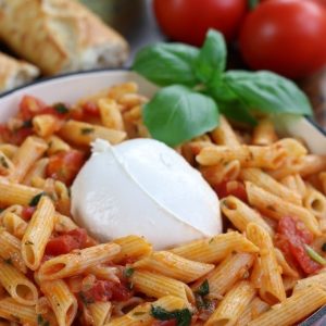 Tomato and Burrata Penne Pasta in an enameled cast iron frying pan.