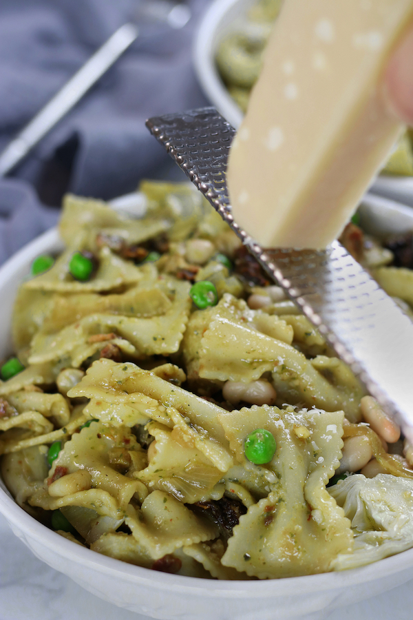 Parmesan being shaved over a bowl of White Bean Pasta.