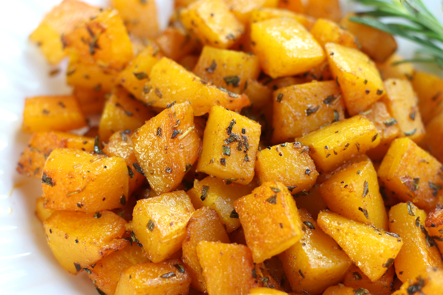 Baked Butternut Squash on a white plate with a fresh rosemary sprig.