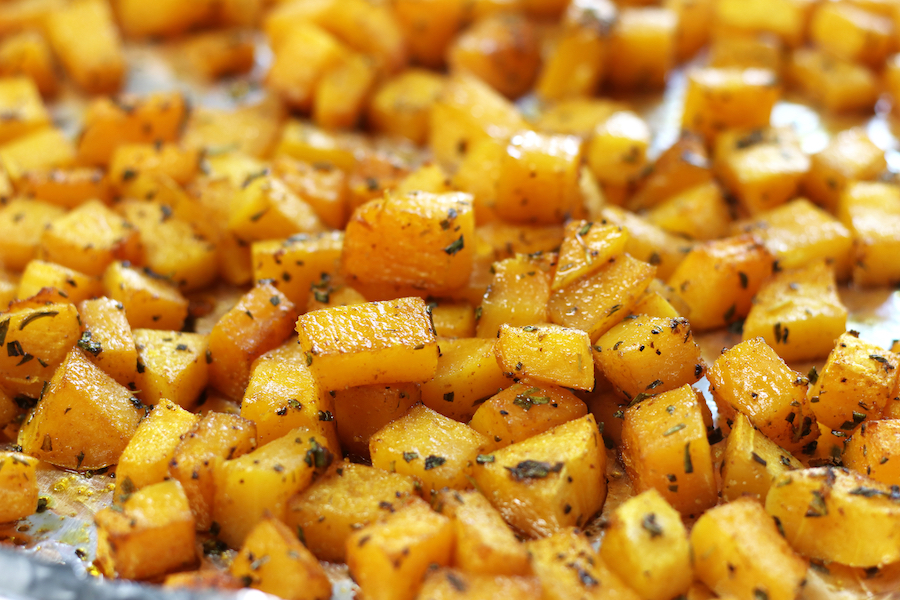 Butternut Squash with rosemary on a cookie sheet lined with foil.