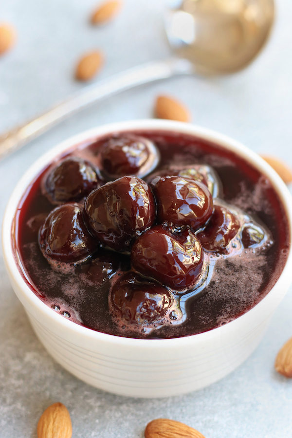 A bowl of Cherry Compote surround by almonds.