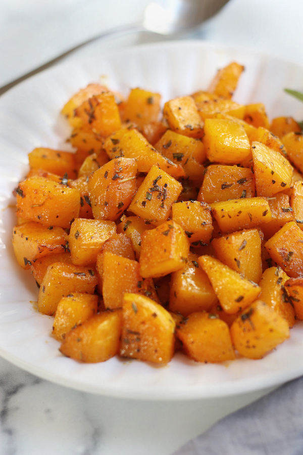 Oven Roasted Butternut Squash served on a white platter sitting on a white counter.