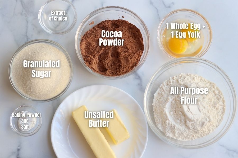 Ingredients for Chocolate Sugar Cookies measured into clear glass bowls.