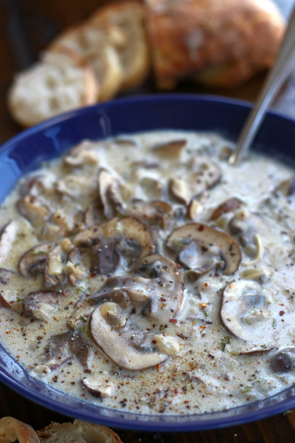 A serving of baguette bread along side a serving of Healthy Mushroom Soup Recipe.