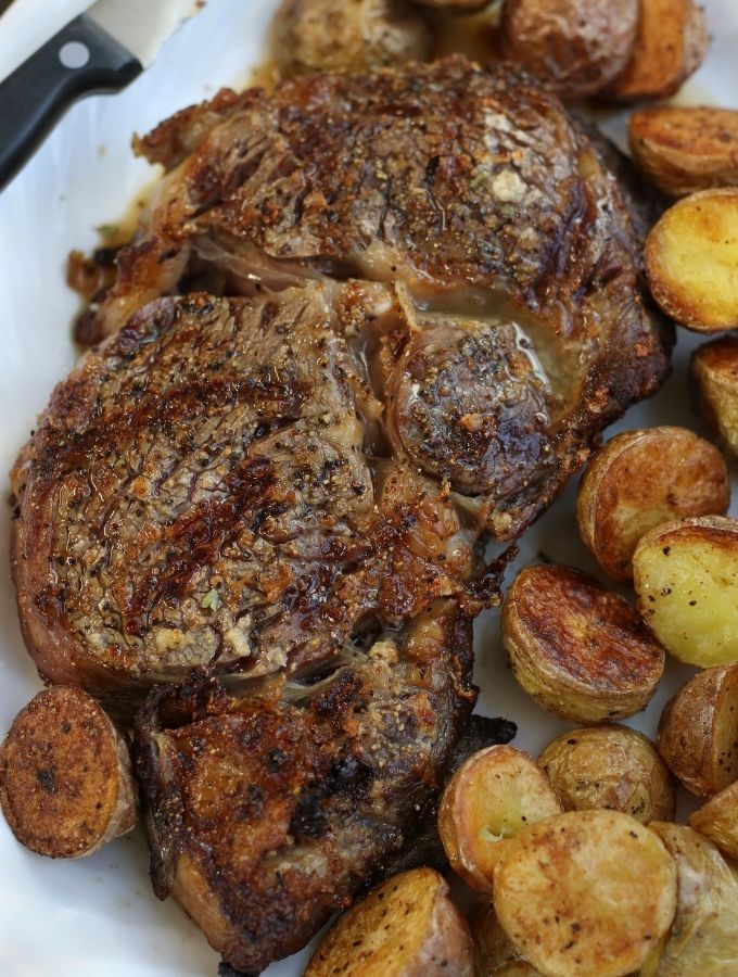 Air Fryer Ribeye on a white plate with crispy potatoes.