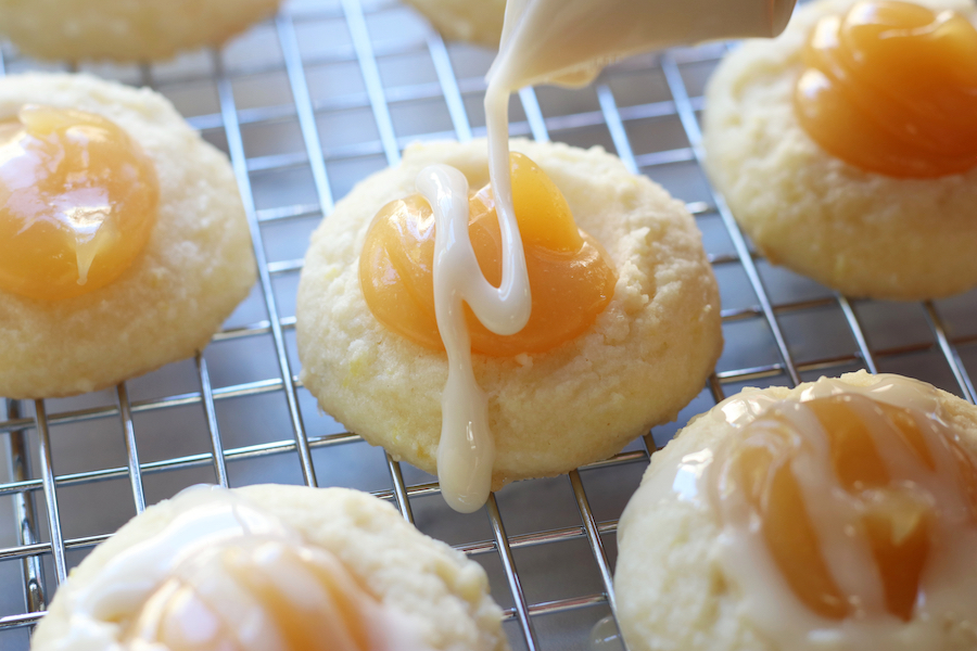 Lemon Cookies being iced with powdered sugar icing.