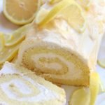 Lemon Roll Cake on a white platter surrounded by lemon slices.