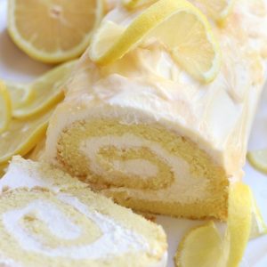 Lemon Roll Cake on a white platter surrounded by lemon slices.