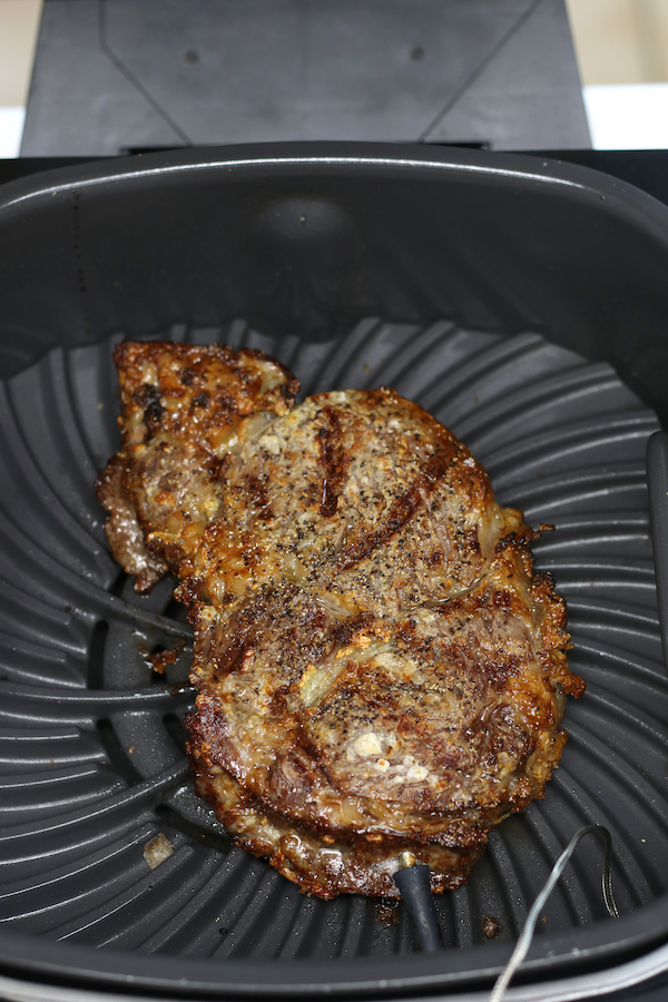 Overhead photo of Ribeye Steak in Air Fryer cooking.