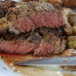 Ribeye Steak that has been cooked in Air Fryer cut in half showing medium rare meat.