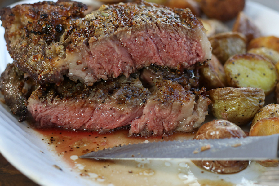 Ribeye Steak that has been cooked in Air Fryer cut in half showing medium rare meat.