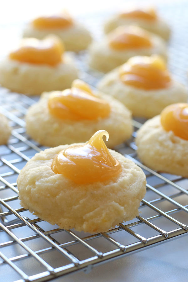 Whipped Lemon Shortbread Cookies with lemon curd lined up on a cooling wrack.