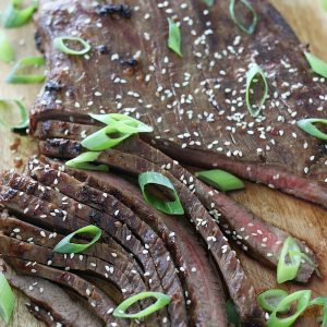 Cooked steak garnished with green onions and sesame seeds that was first marinated with Asian Beef Marinade recipe.